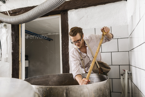 Worker mixing ingredients in vat - Stock Photo - Images