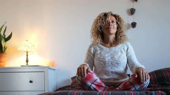 Meditating woman sitting cross-legged on her bed