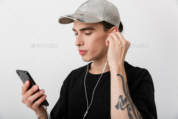 Portrait of handsome man wearing black clothes listening to music with cellphone and earphones