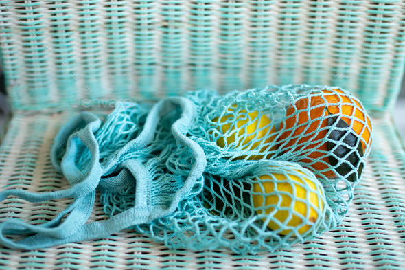 Fruit in blue string mesh reusable bag on the back of chair, zero waste eco concept