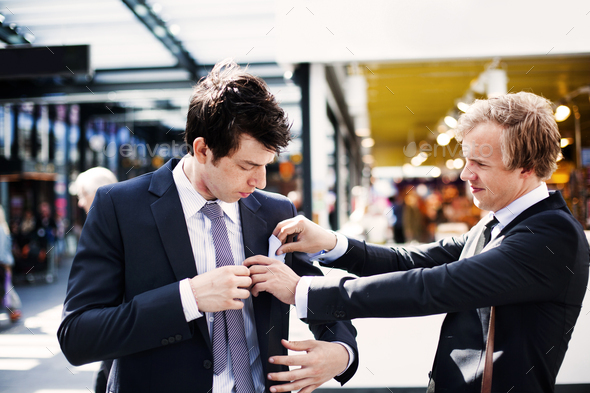 Businessman adjusting colleague\'s pocket square while standing outdoors