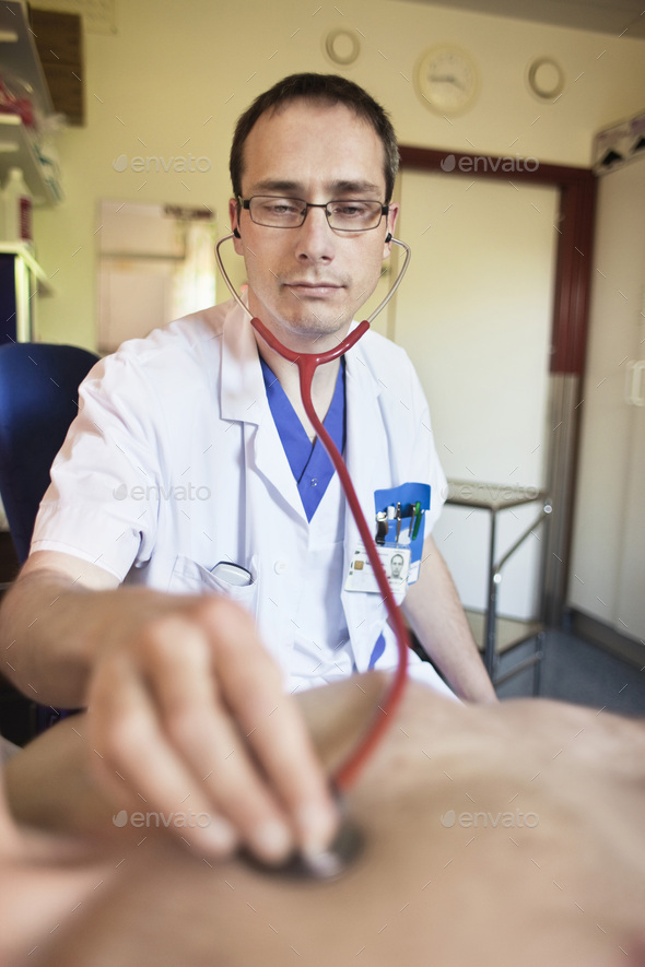 Doctor listening to heartbeat of patient through stethoscope in hospital