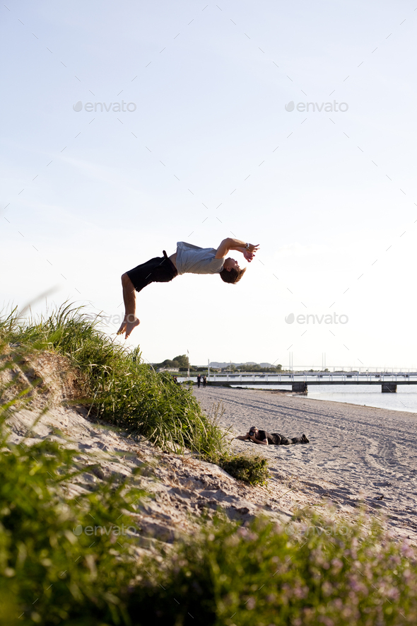 Full length of young man doing back flip at beach