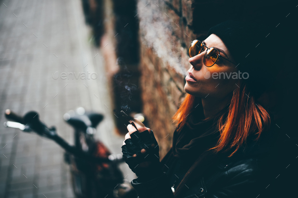 Red hair woman in black rock style leather jacket at the autumn city