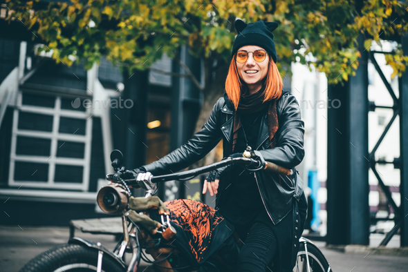 Red hair woman in black rock style leather jacket at the autumn city