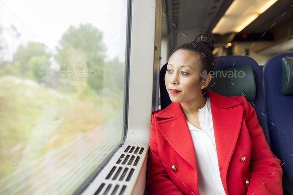 Woman in red coat sitting and looking through train window