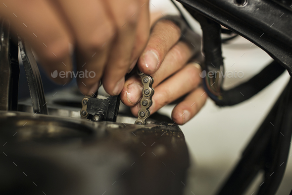 Close up of man holding chain during repair of motorcycle