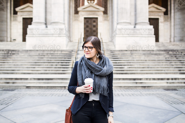 Confident businesswoman holding coffee cup standing in front of New York Public Library