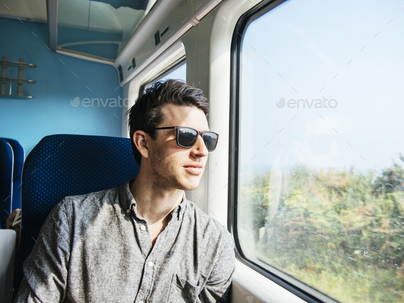 Thoughtful businessman in sunglasses looking through train window