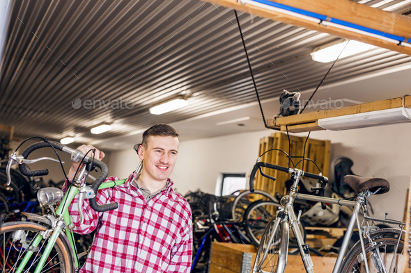 Happy mechanic carrying bicycle in workshop