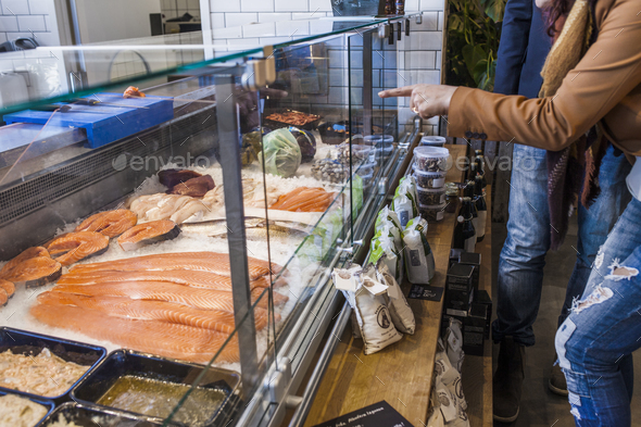Midsection of woman pointing at seafood in supermarket