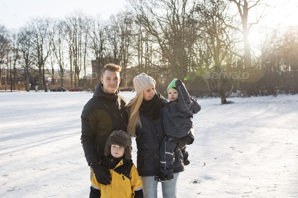 Portrait of young man with family standing on snow covered field