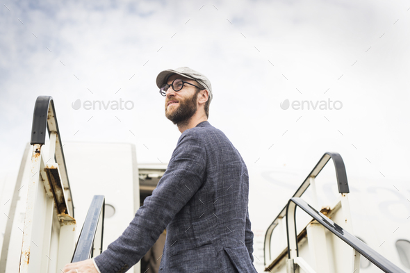 Side view of businessman standing on boarding stairs against sky