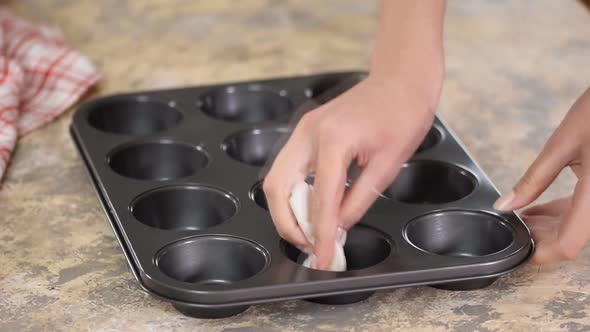 Woman Spreading Oil on Muffins Moulds To Make Delicious Cupcakes, Muffins. Homemade Pastries. alt