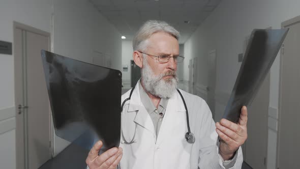 Cheerful Senior Male Doctor Smiling To the Camera While Comparing Two Xray Scans