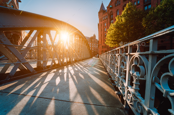 Metal arch bridge in the Speicherstadt of Hamburg with sunburst light during sunset golden hour - Stock Photo - Images