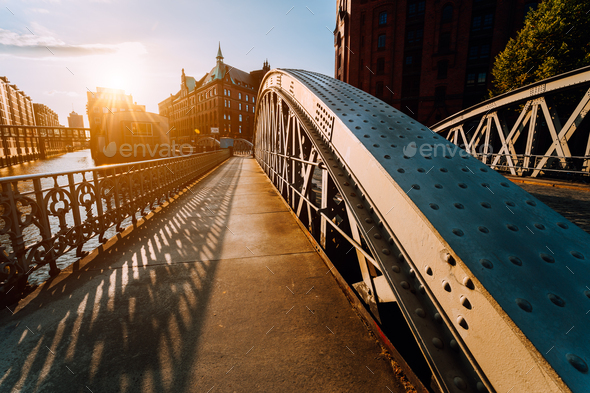 Metal arch bridge with rivets in the Speicherstadt of Hamburg during sunset golden hour with - Stock Photo - Images