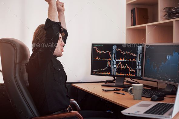 Young stock trader stretching hands at workplace, he first achieved great success on stock market
