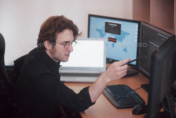 Male programmer working on desktop computer with many monitors at office in software develop company