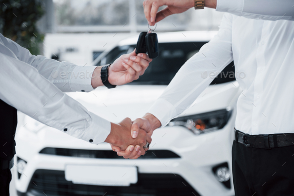 Close up of sales manager in black suit selling the car to the customer.