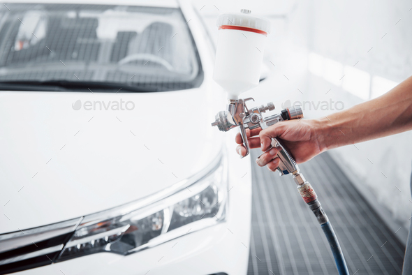 gun with paint in the hands of a man to paint a car
