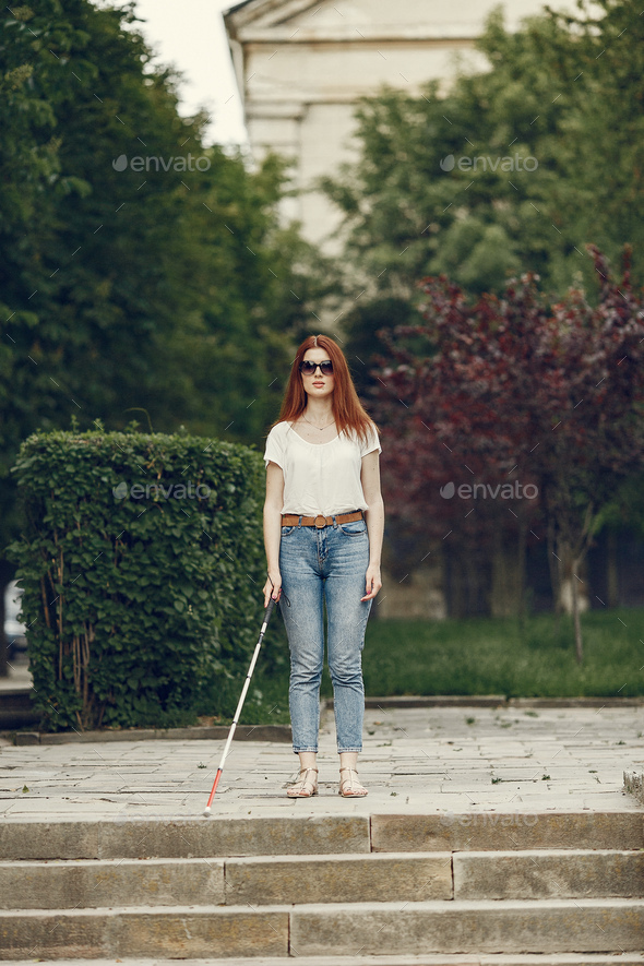 Young blind person with long cane walking in a city Stock Photo by  prostooleh