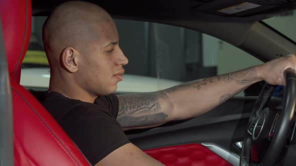 Cheerful Handsome African Man Smiling to the Camera While Sitting in His Car alt