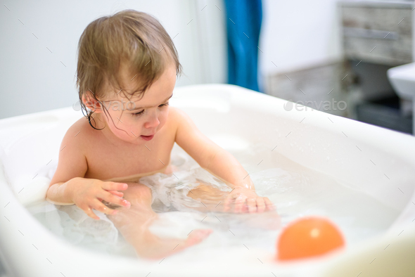1 year old Baby in bathtub taking bath in bathroom. Hygiene concept