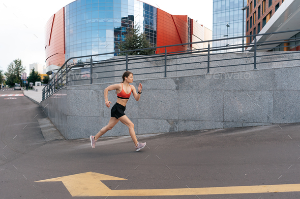 Female fitness model training outside in the city Stock Photo by diignat