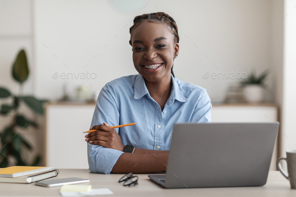 Office Worker. Smiling Black Secretary Woman Posing At Workplace, Sitting At Desk With Laptop, Free Space