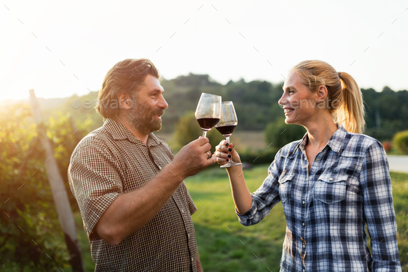 Happy young people tasting wine in vineyard