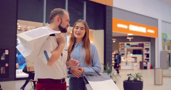 Beautiful Young Couple Standing and Discussing Something in the Mall alt