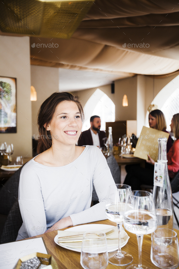 Happy woman sitting at table in Lebanese restaurant