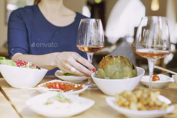 Midsection of woman holding wineglass at table in Lebanese restaurant