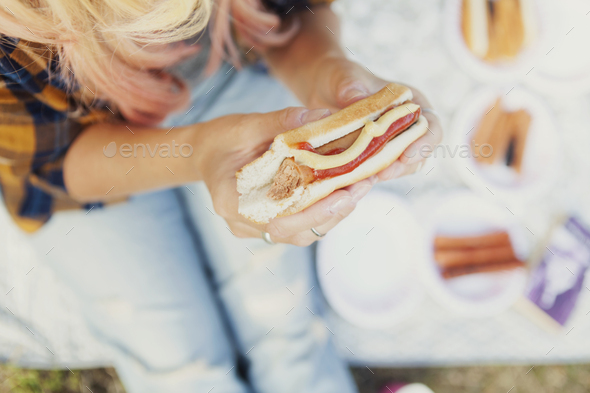 High angle midsection of woman holding hot dog outdoors
