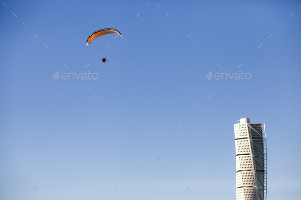 Low angle view of parasail in mid-air and Turning Torso skyscraper against clear blue sky