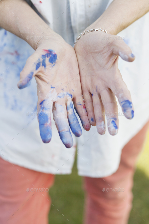 Midsection of senior female painter showing messy hands outdoors