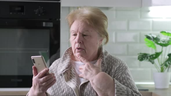 Serious Elderly Woman Talking Online Video Call with Friends Children or Doctor Using Mobile Phone alt