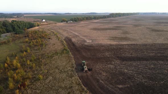 Aerial view, drone view of green tractor with plough working on a field, alt