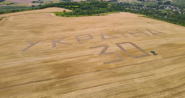 A Tractor Plowed An Inscription Dedicated To The Independence Day Of Ukraine On A Wheat Field alt