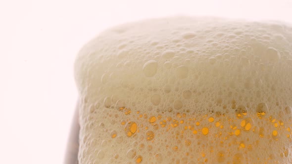 Glass of beer with froth in slow motion on white background