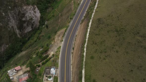 Aerial view that shows an empty highway along a hillside with a bright yellow stripe in the middle alt