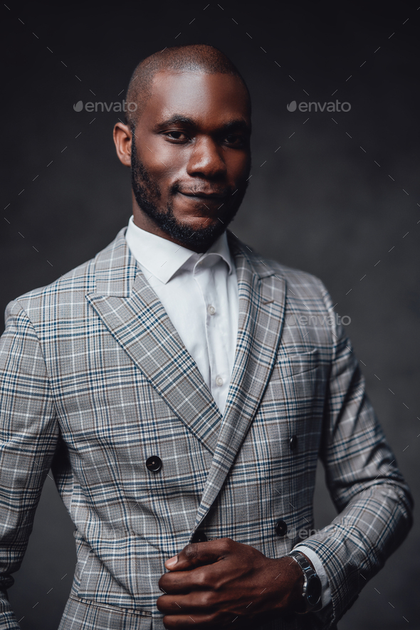 Black serious man in dress staying and looking at camera