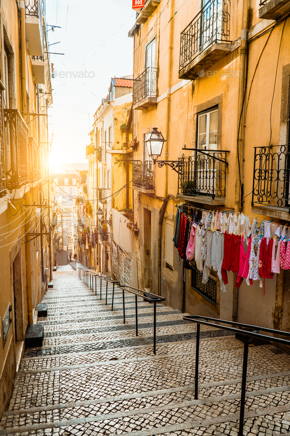 Staircase in the cobblestone street in Lisbon. Hanging laundry in typical narrow street. Sunset in - Stock Photo - Images
