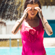 Young girl wear bikini standing under the outdoor pool shower