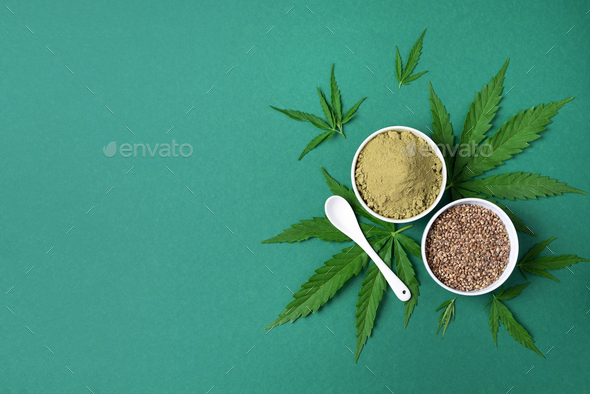 Hemp products – cannabis leaves, seeds, hemp protein powder, flour on green background. Top view. Copy space. Flat lay.