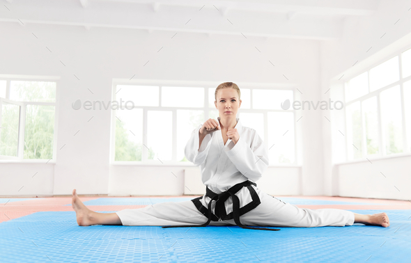 Portrait of karate girl black belt degree, stretching her legs before hard training