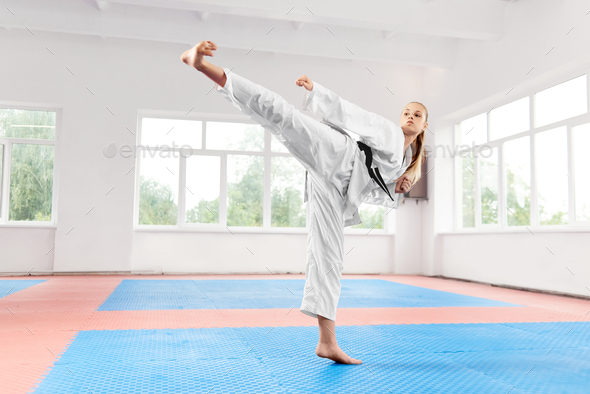 Woman performing martial arts high kick at fight class