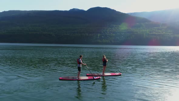 Couple on stand up paddle board oaring in river 4k alt