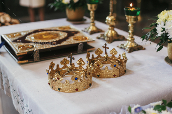 Golden crowns and bible on holy altar during wedding ceremony